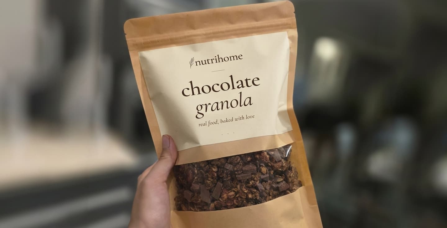 NutriHome Chocolate Granola pouch held up, branded label clearly visible
